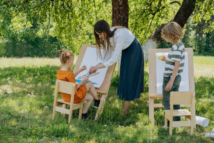 Femeie si copii care picteaza