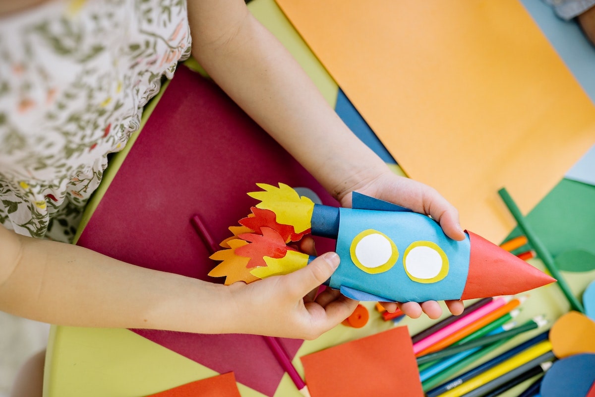 Copil care face origami cu hartie colorata